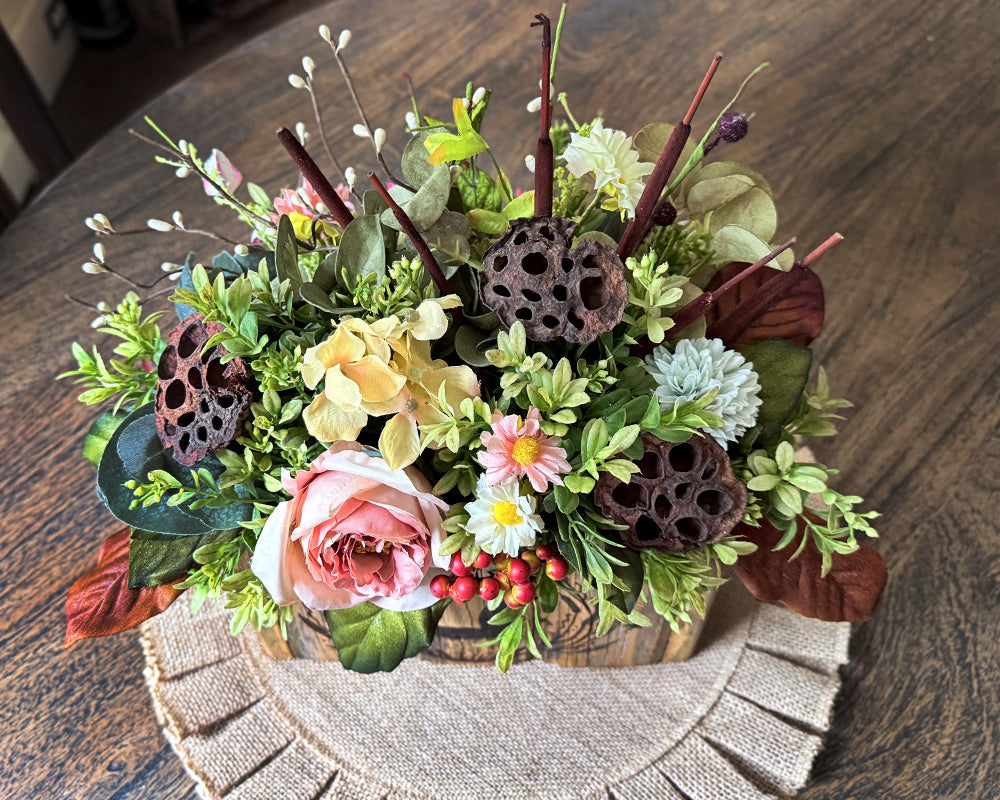 Decorative floral arrangement with cattails, lotus pods  and  faux  flowers on a dinning room table.