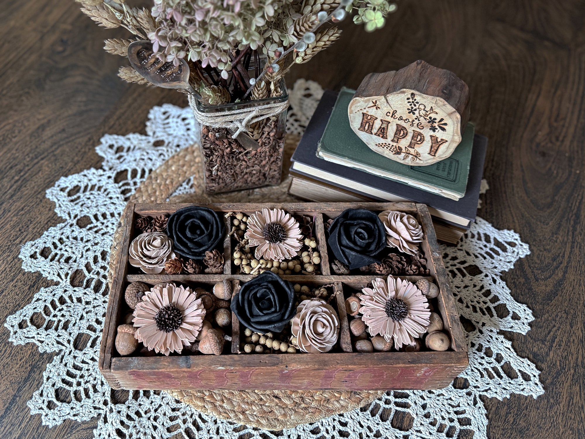 Decorative vintage box with flowers, books, and a vase on a lace doily