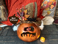 Decorative pumpkin ghost with a hat and candle on a wooden surface