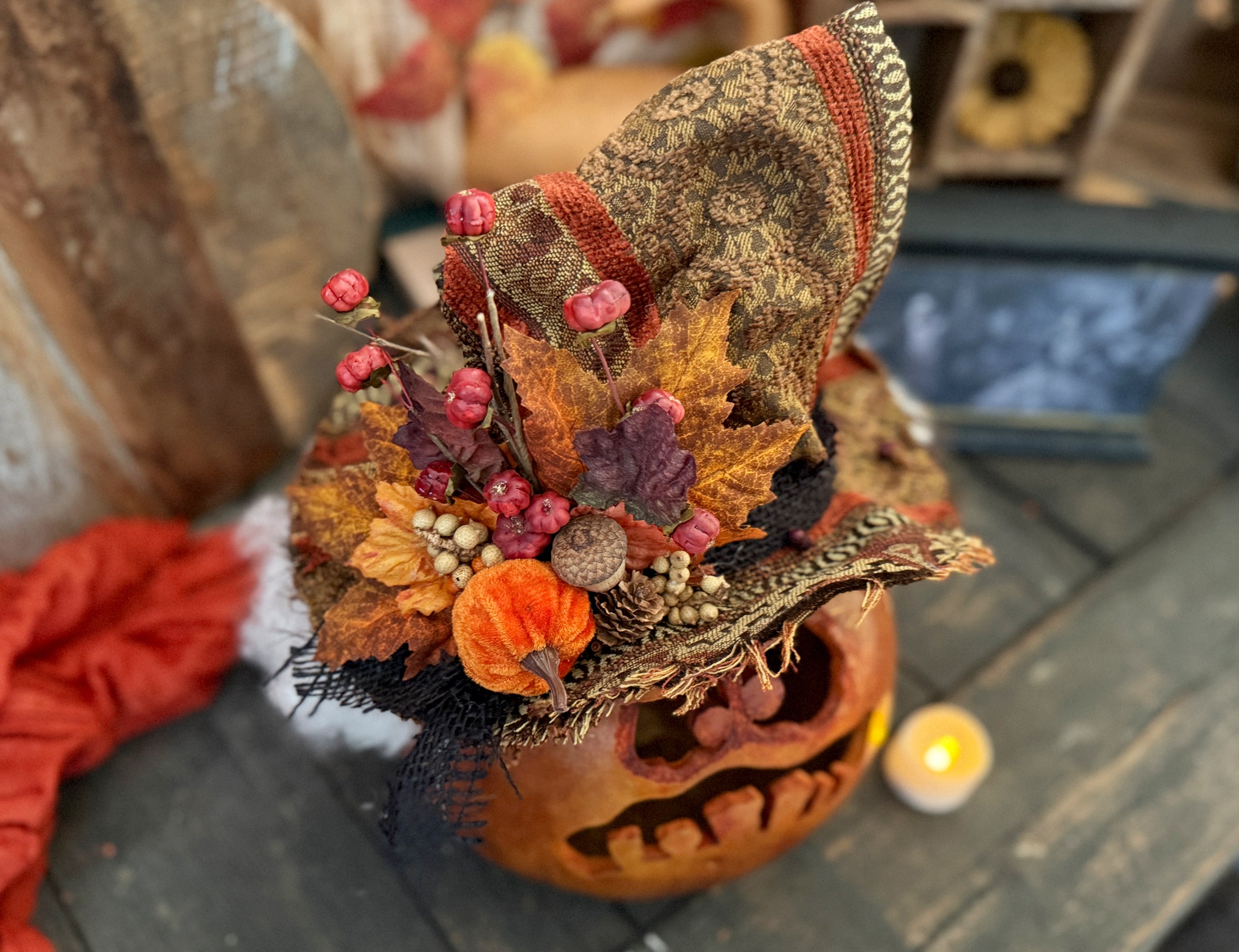 Decorative pumpkin with autumn-themed embellishments on a wooden surface.