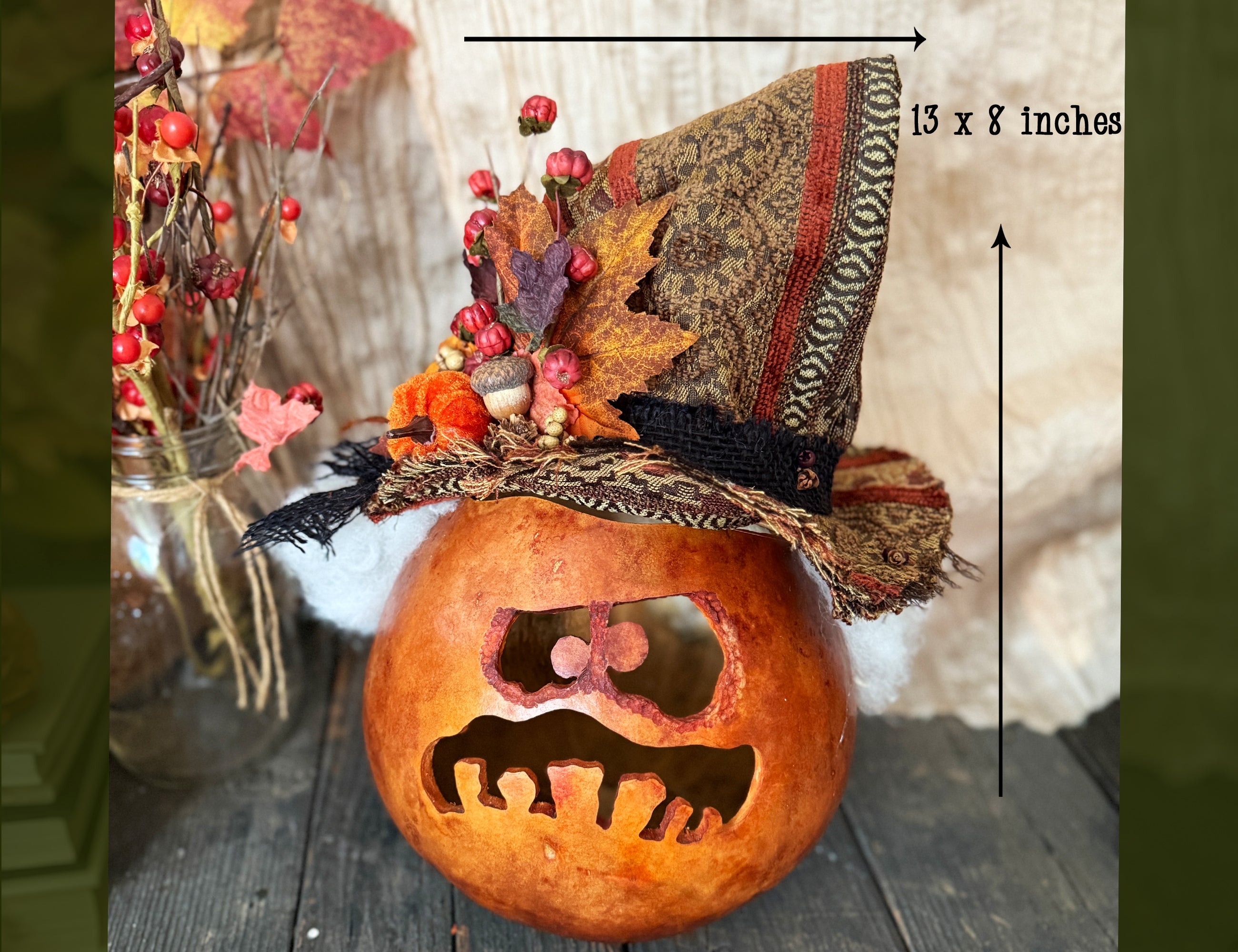 Decorative pumpkin with a fall hat and autumn leaves on a wooden surface.