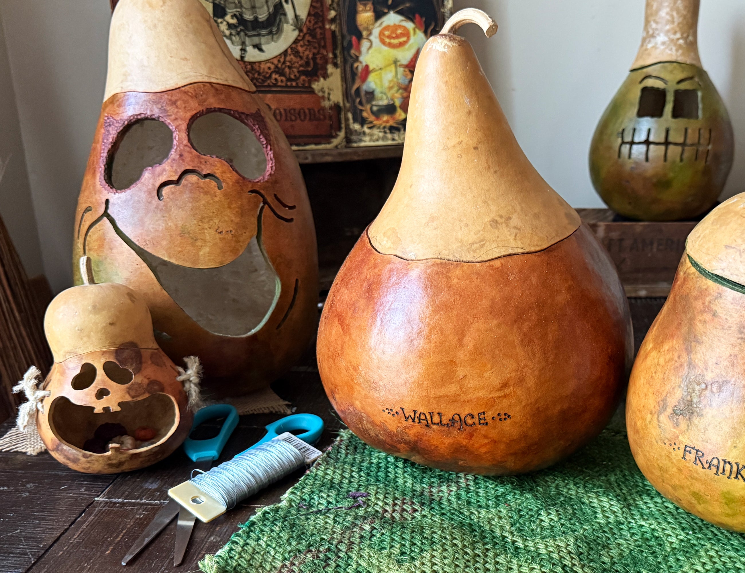 Gourd carvings with Halloween designs on a table with a green cloth.