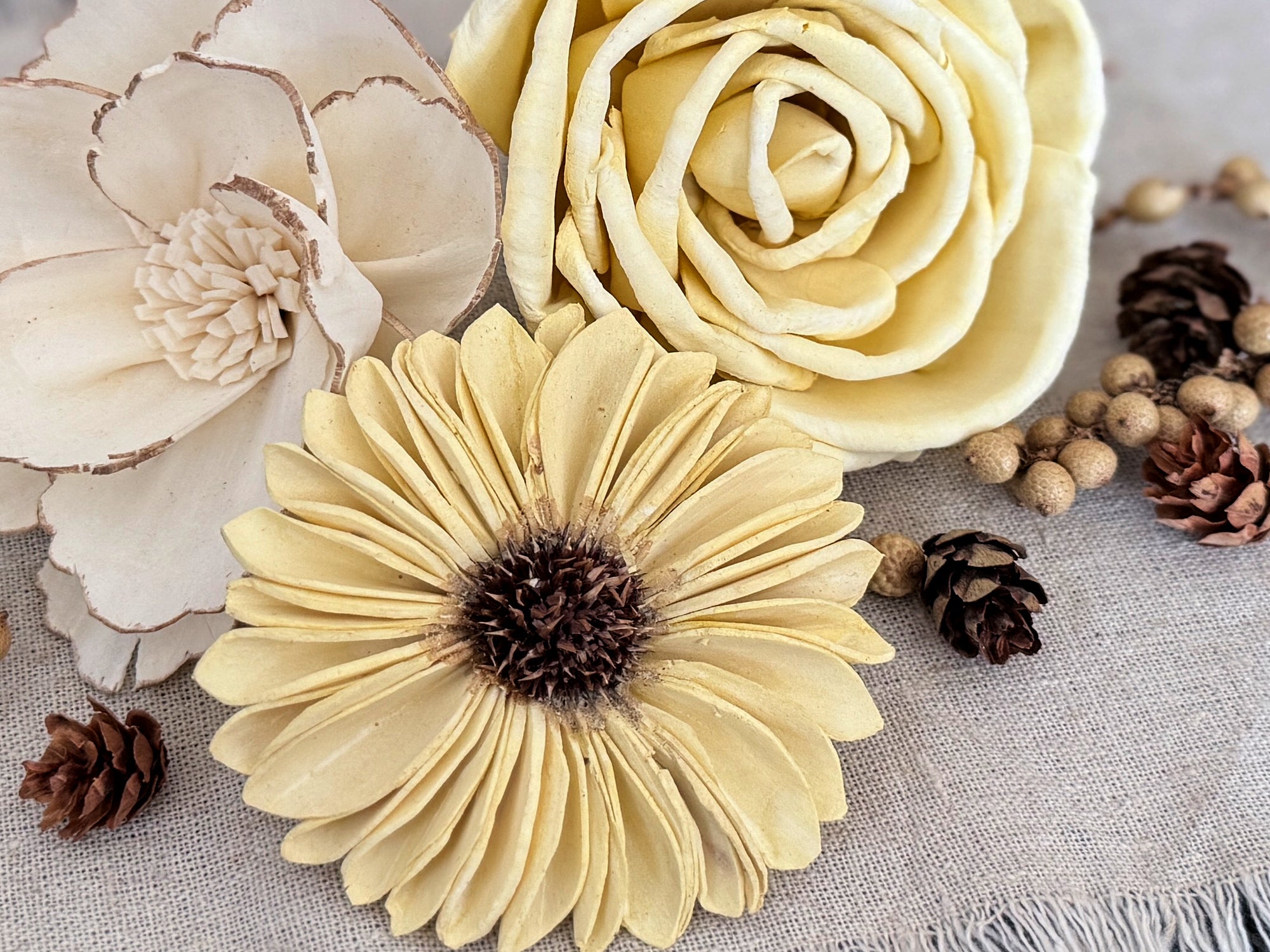 Close-up of decorative flowers and pinecones on a textured surface
