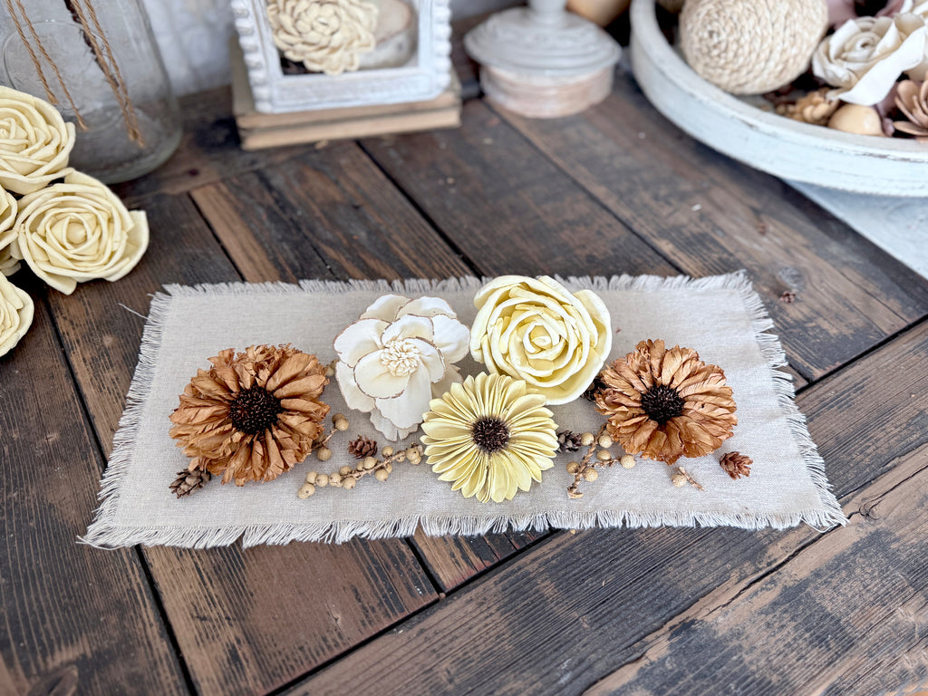 Decorative table runner with flowers and natural table scatter on a wooden surface