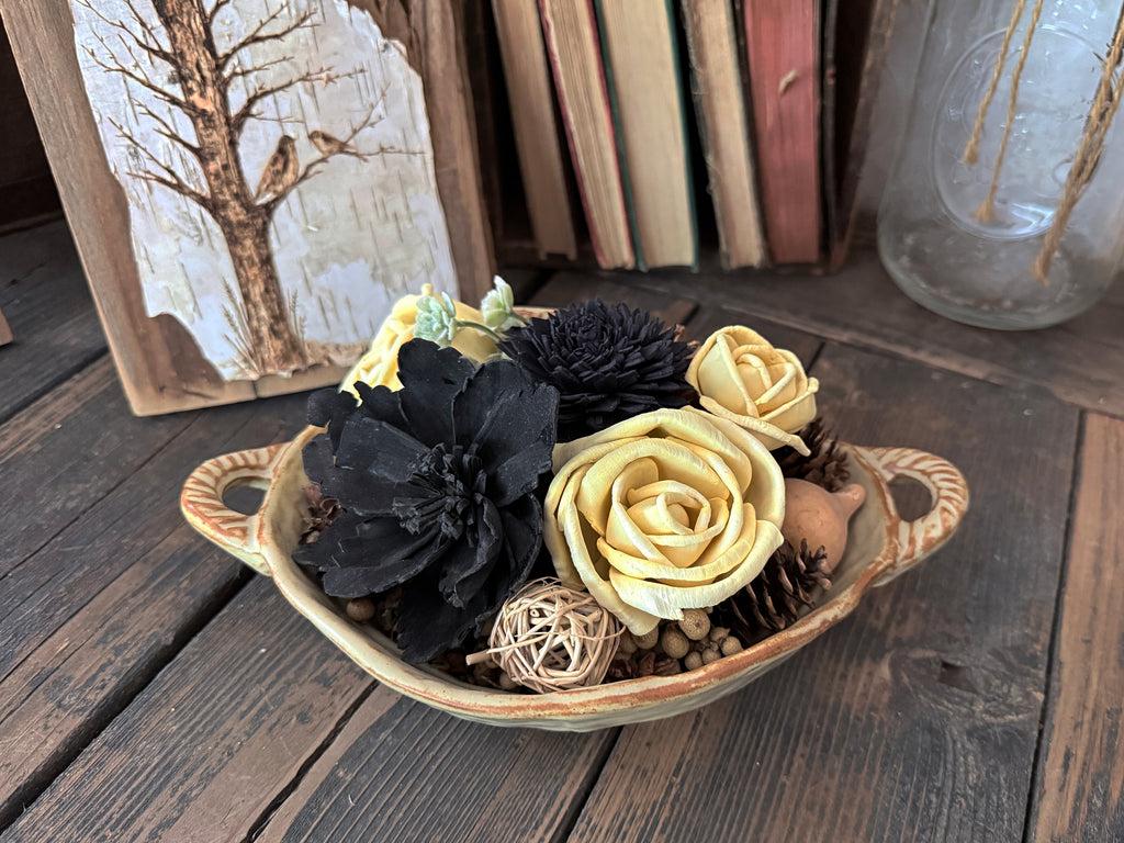 Decorative ceramic bowl with black and yellow flowers on a wooden surface