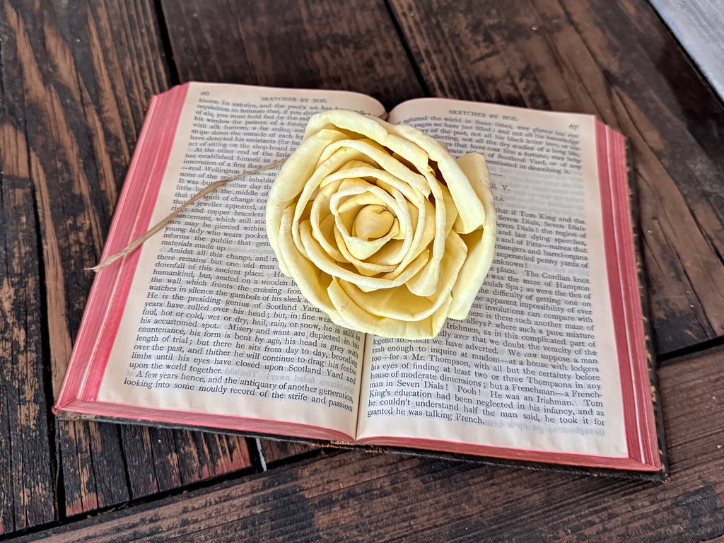 Yellow rose on an open book on a wooden surface
