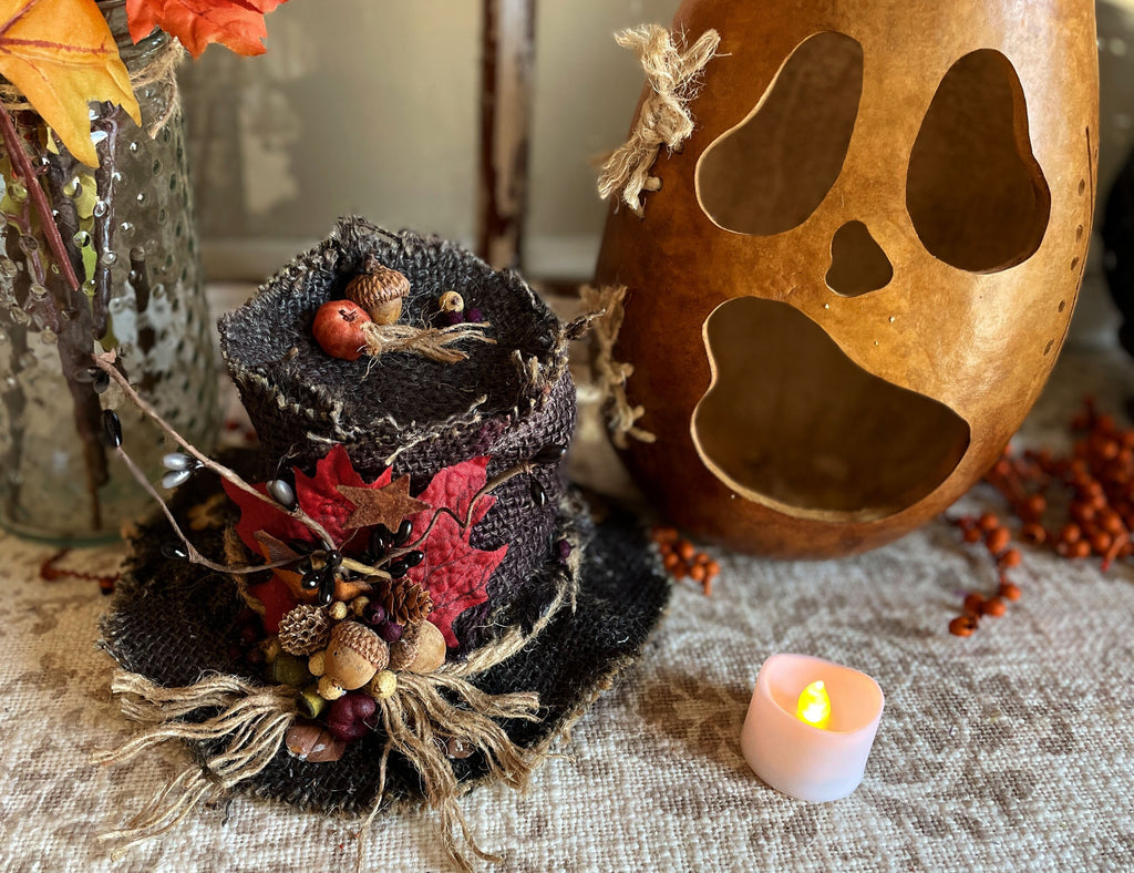 Decorative Halloween potpourri with a wooden ghost decoration and lit candle on a textured surface.