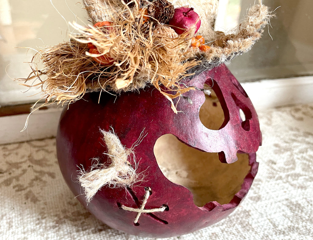 Decorative purple pumpkin with straw and berry top on a textured surface