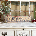 Decorative sign with 'It's a Wonderful Life' text on a vintage cabinet with Christmas decorations.