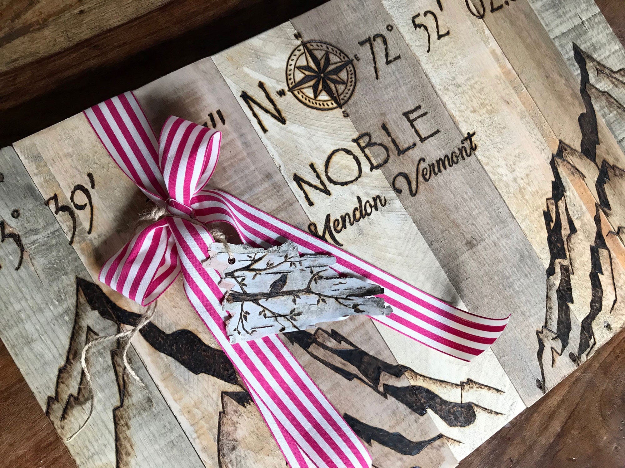 Decorative item with a pink and white striped ribbon on a wooden surface with text and graphics.