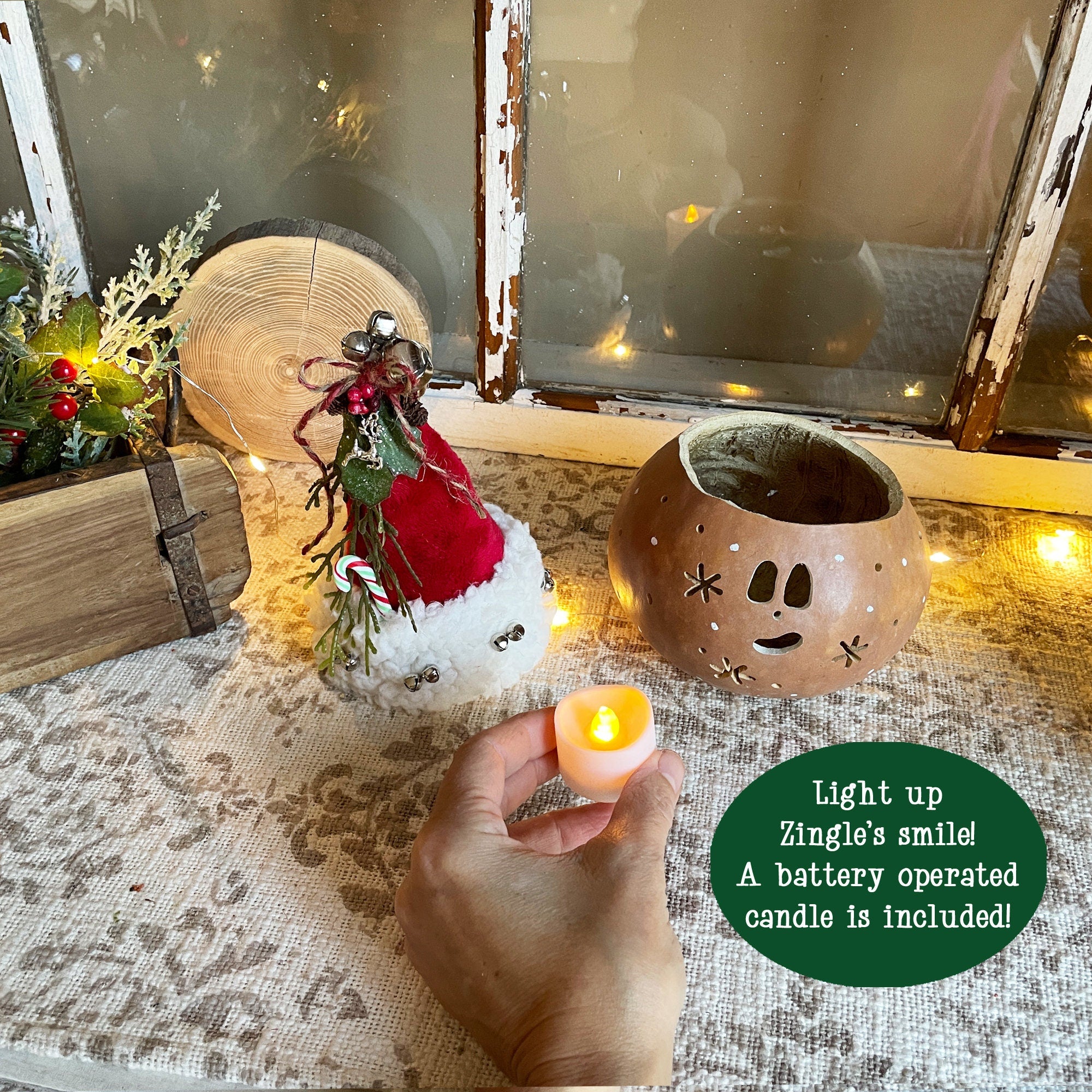 Decorative setup with a small tree, candle holder, and battery-operated candle on a textured surface.