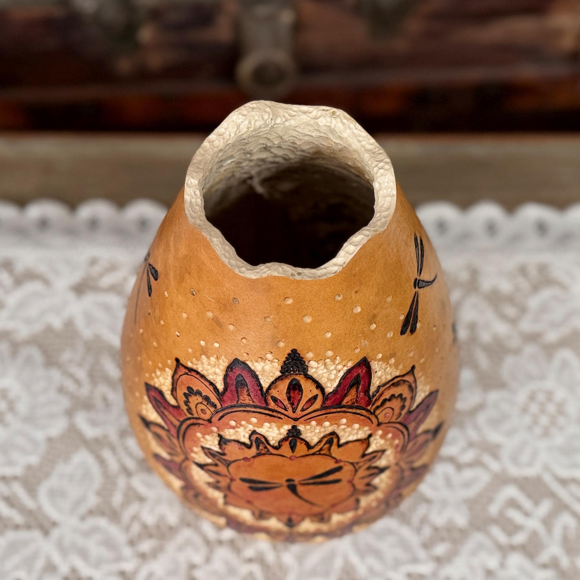 Decorative gourd vase with floral design on a textured surface