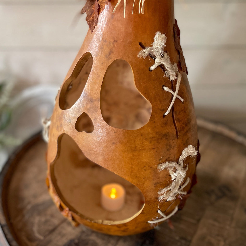Decorative gourd with a candle inside on a wooden surface