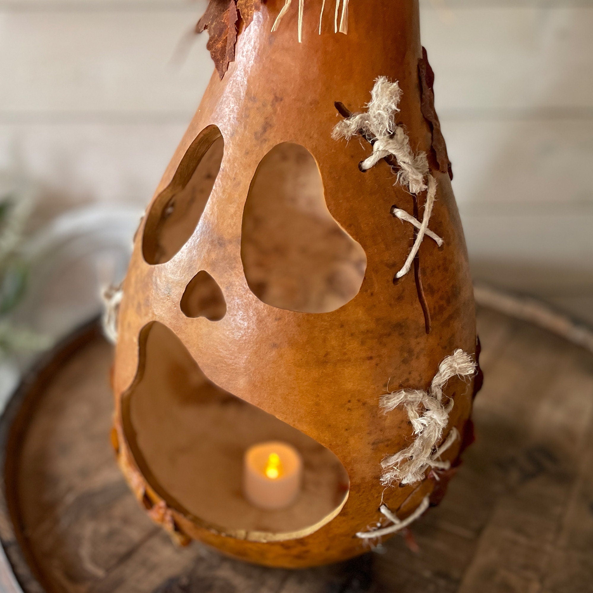 Decorative gourd with a candle inside on a wooden surface
