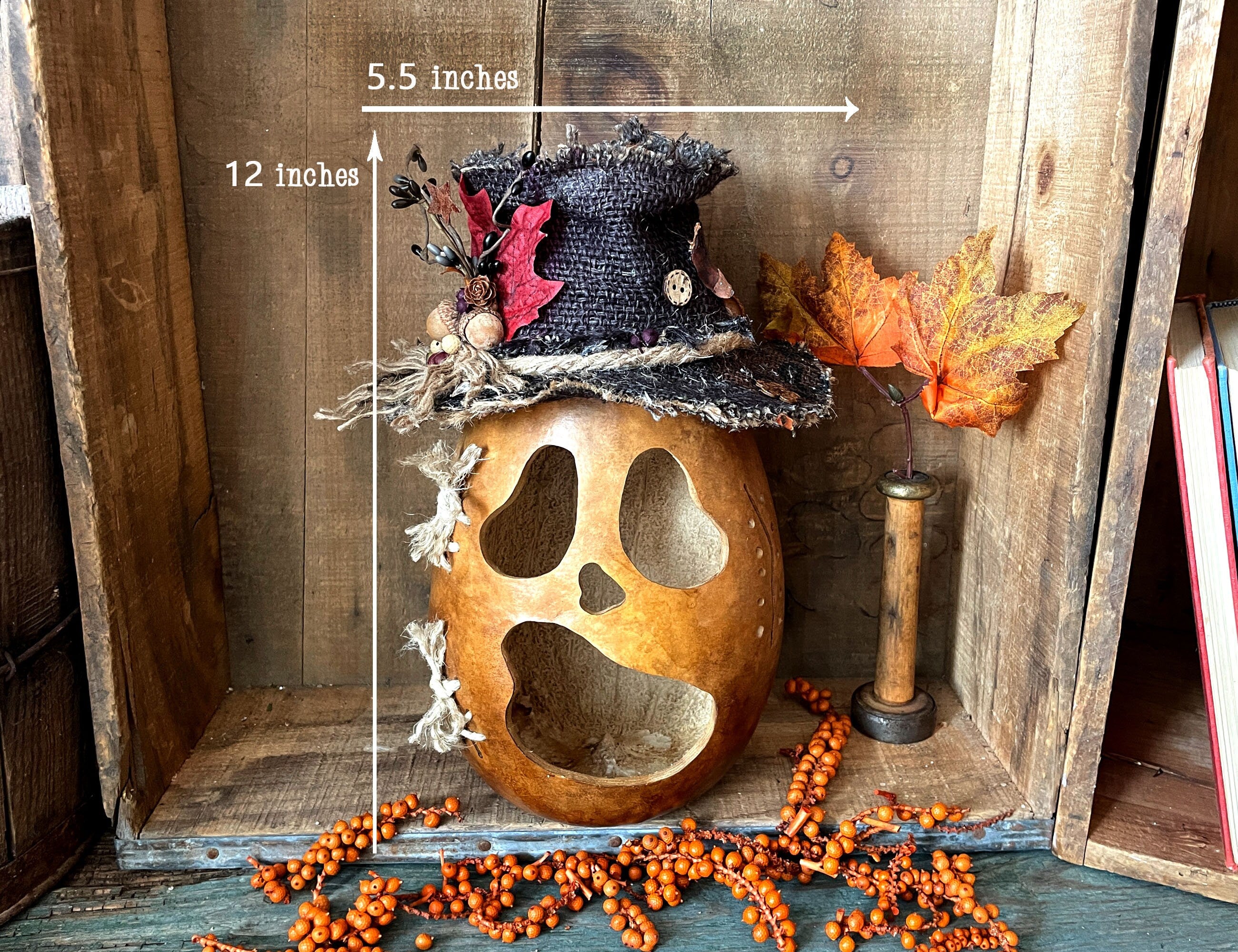 Decorative pumpkin with a top hat and measurements on a wooden surface