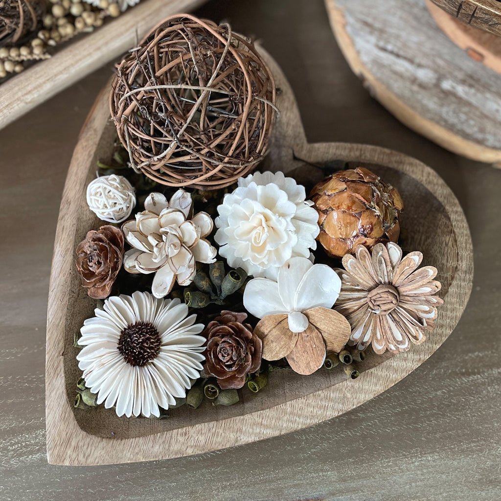 Heart-shaped wooden tray with decorative flowers and a ball of twine on a wooden surface.