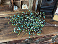 Bouquet of turquoise and green flowers on a wooden surface with vintage items in the background