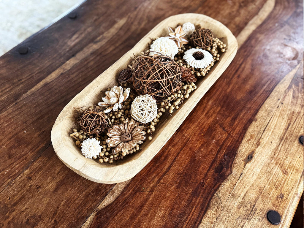 Decorative arrangement of flowers and decorative elements in a wooden bowl on a wooden surface
