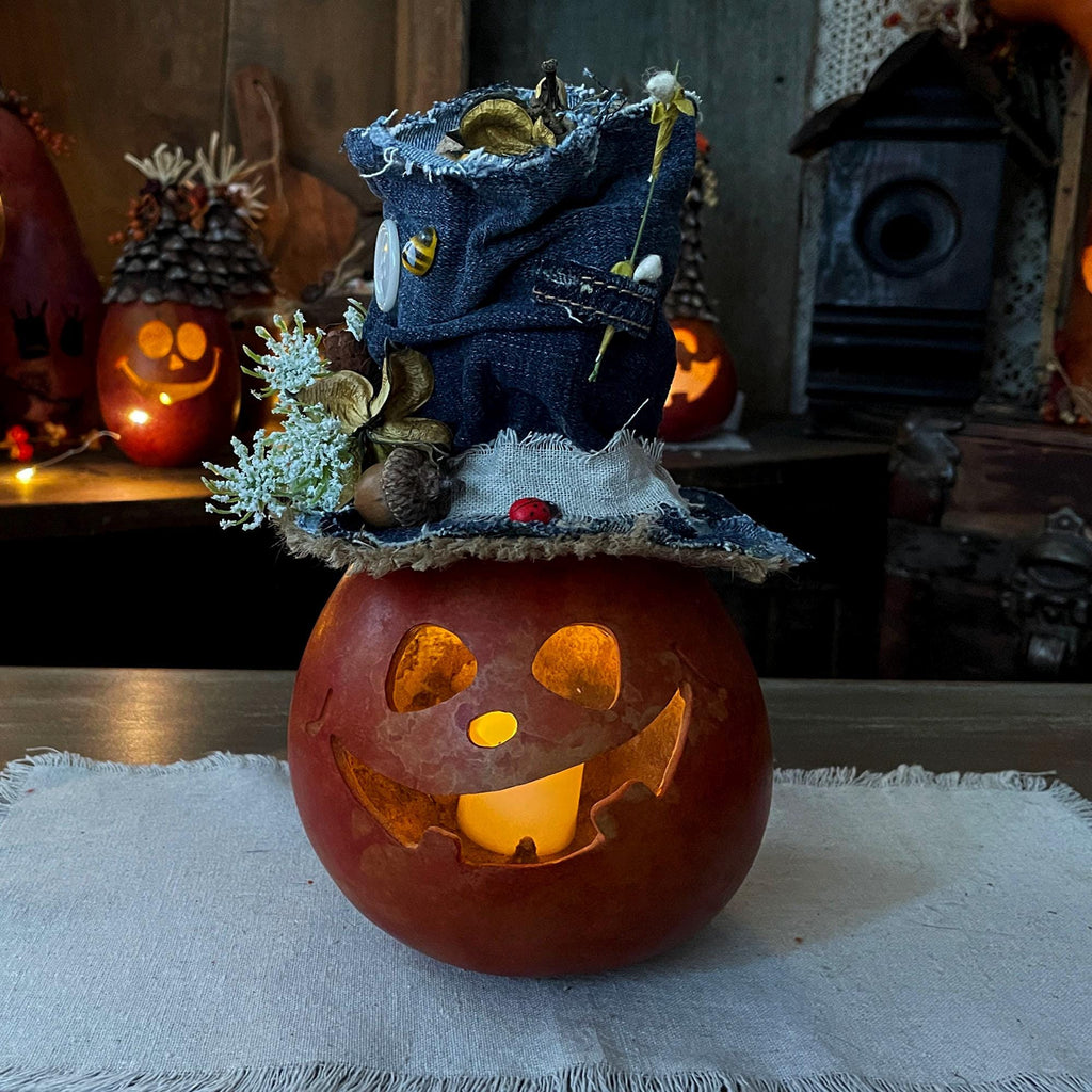 Decorative pumpkin with a small figure on top, surrounded by Halloween-themed decorations.