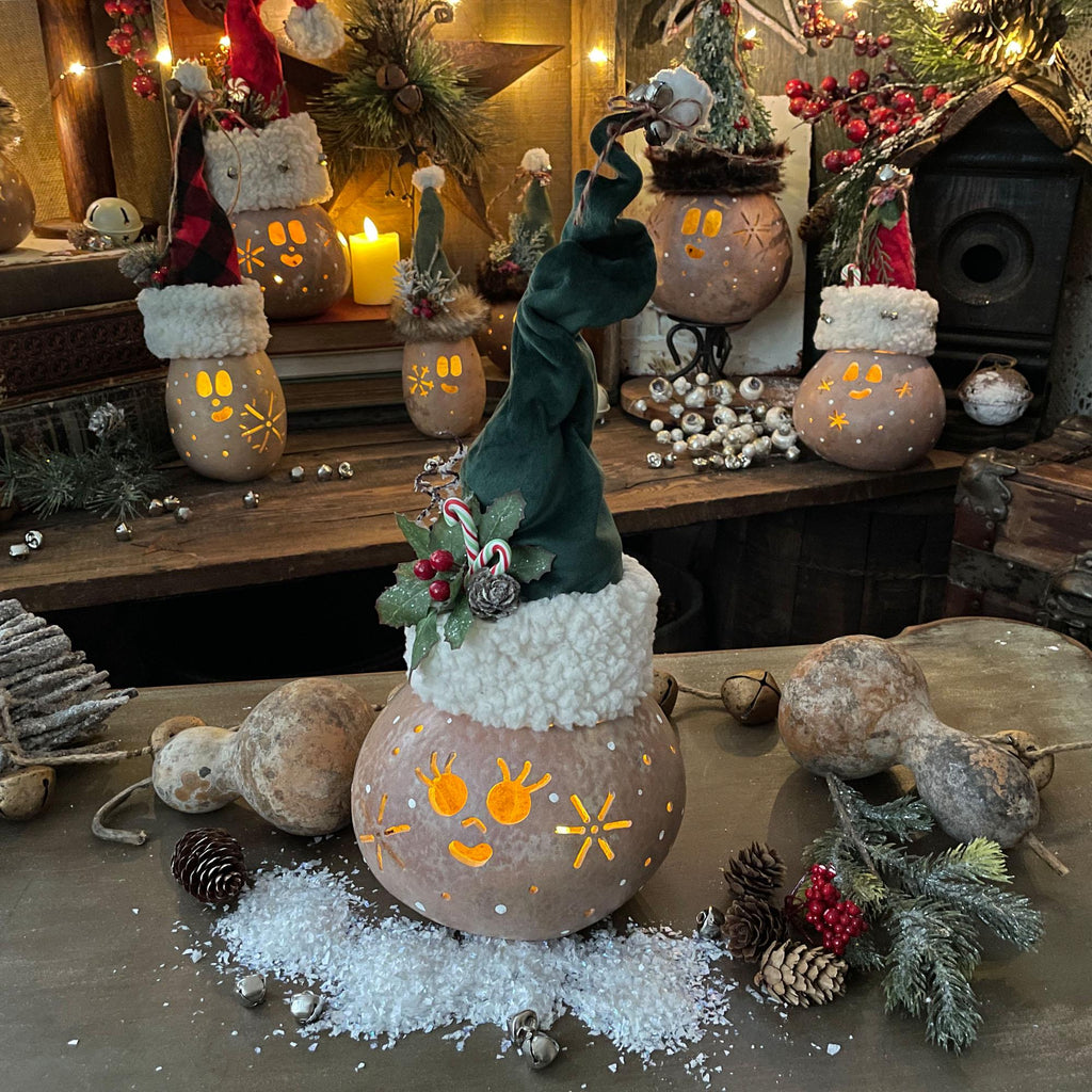 Decorative setup with lanterns, elves, and Christmas decorations on a wooden surface.