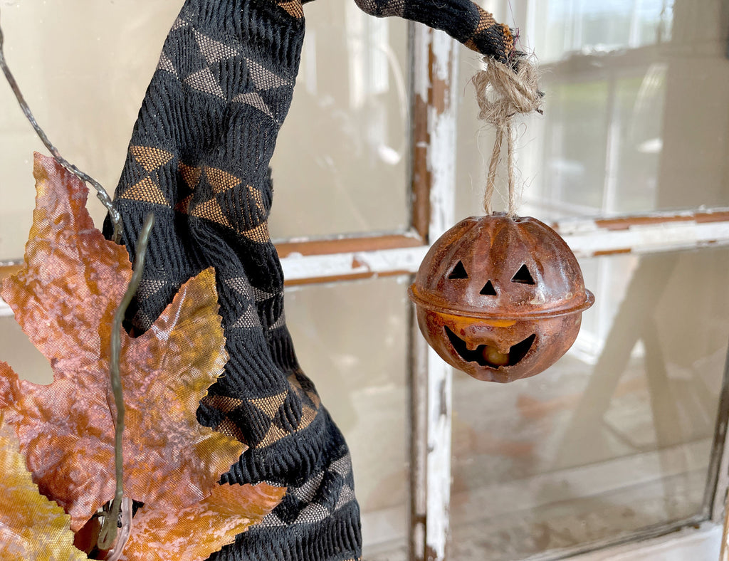 Decorative Halloween pumpkin lantern with a witch's leg and autumn leaves.