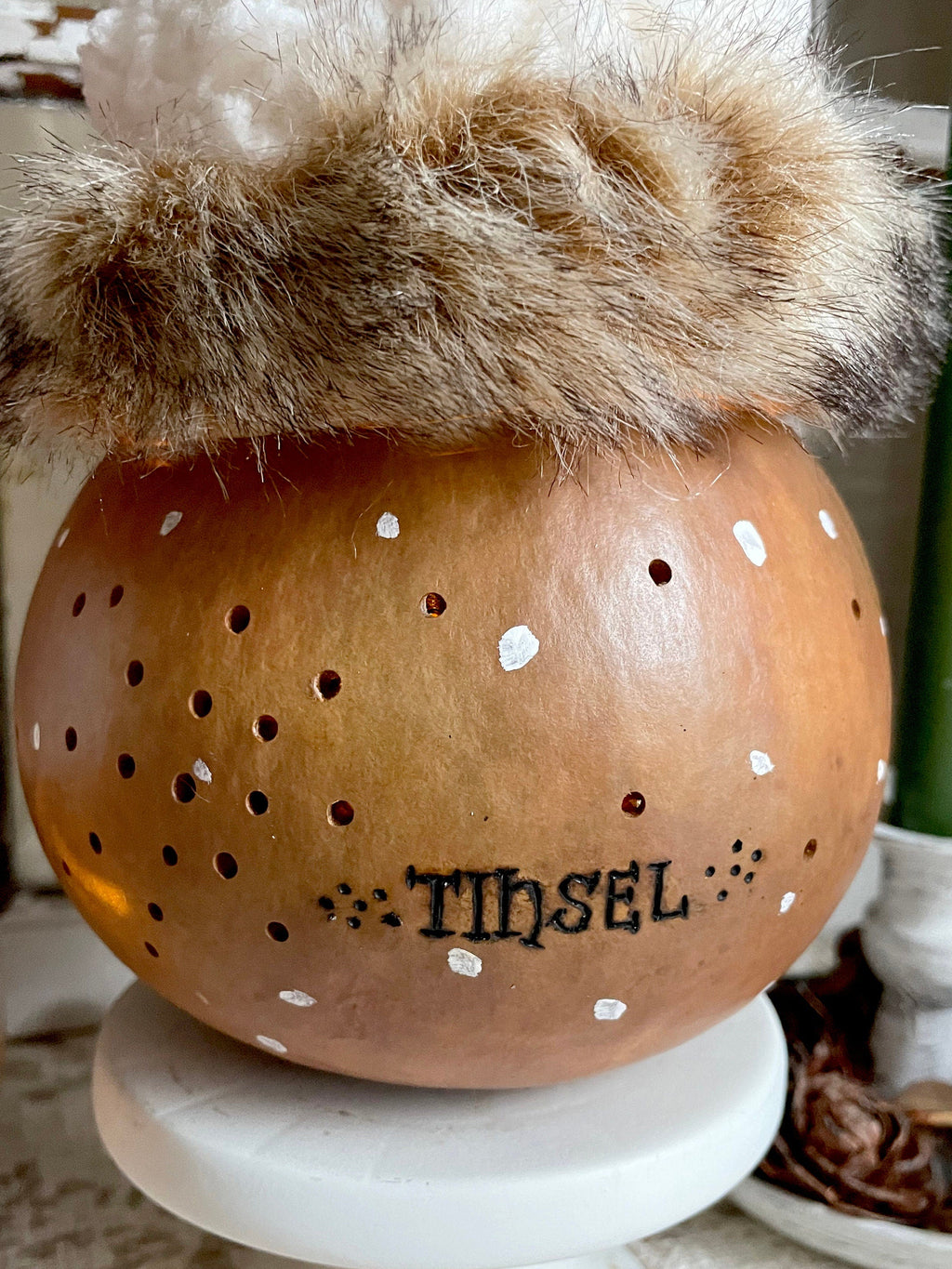 Decorative gourd with fur top and 'THESL' branding on a white surface.