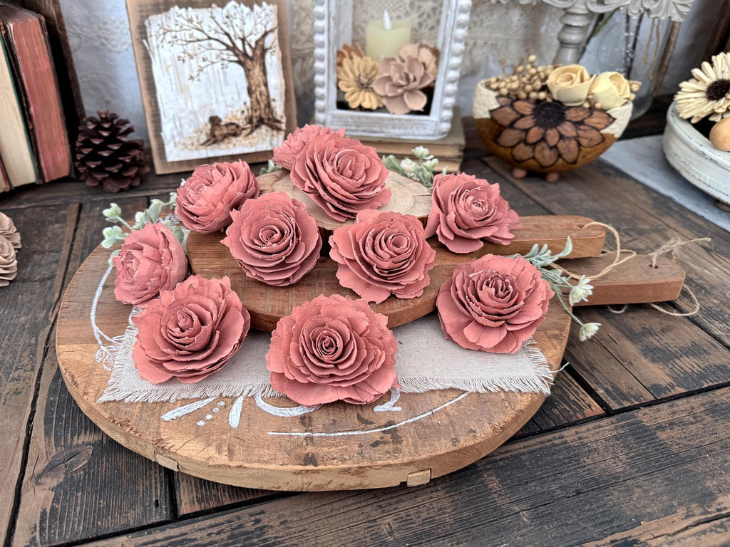 Decorative display of pink wood flowers on a wooden board with a rustic background.
