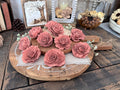 Decorative display of pink wood flowers on a wooden board with a rustic background.