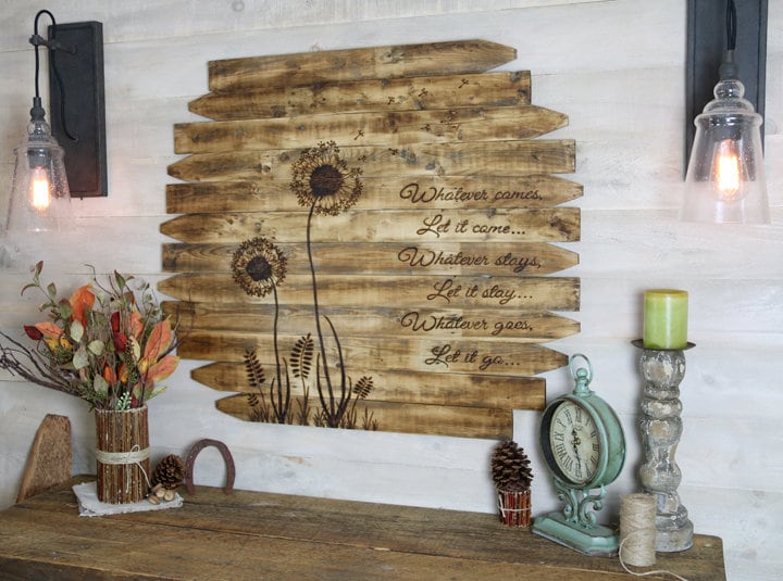 Wooden wall art with floral designs and text on a rustic shelf.