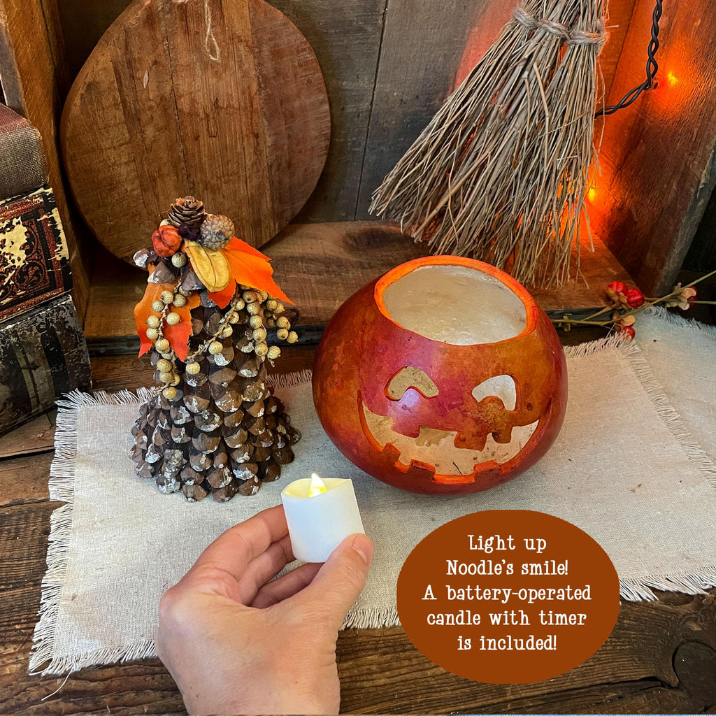 Decorative pumpkin with carved faces on a wooden surface, surrounded by Halloween decorations.