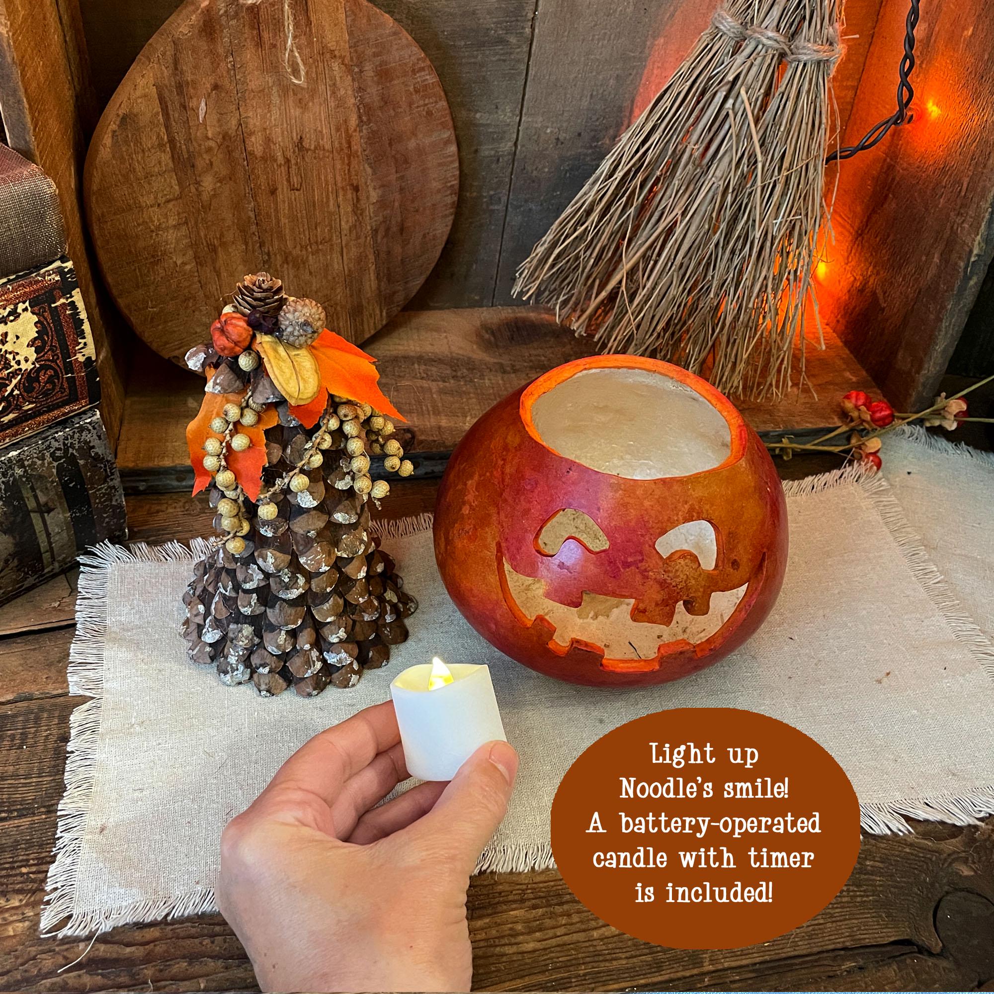 Decorative pumpkin with carved faces on a wooden surface, surrounded by Halloween decorations.