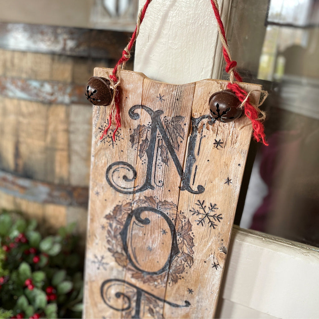 Wooden sign with 'Merry Christmas' decoration hanging indoors.