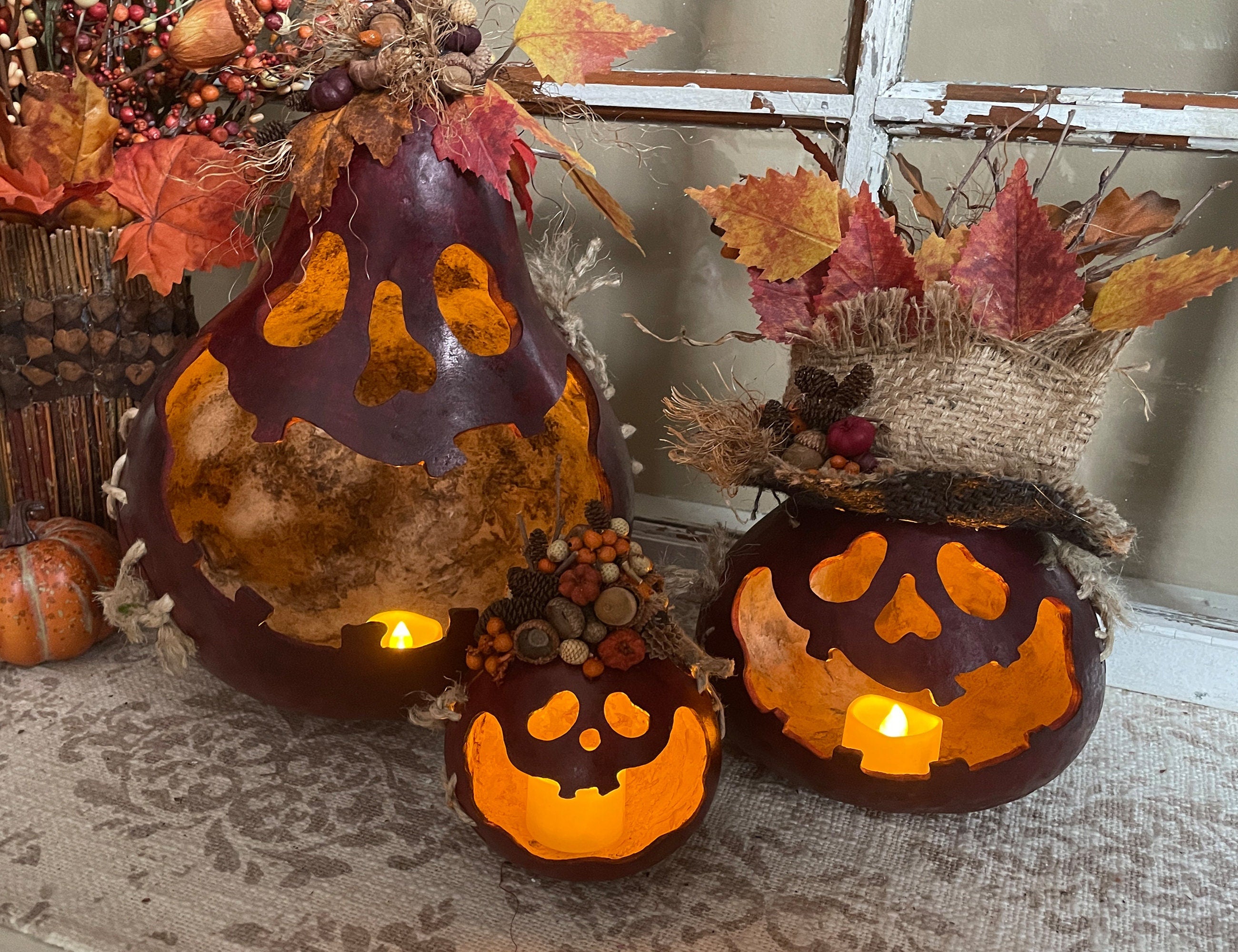 Decorative pumpkins with glowing lights on a textured surface with autumn leaves and a rustic background.