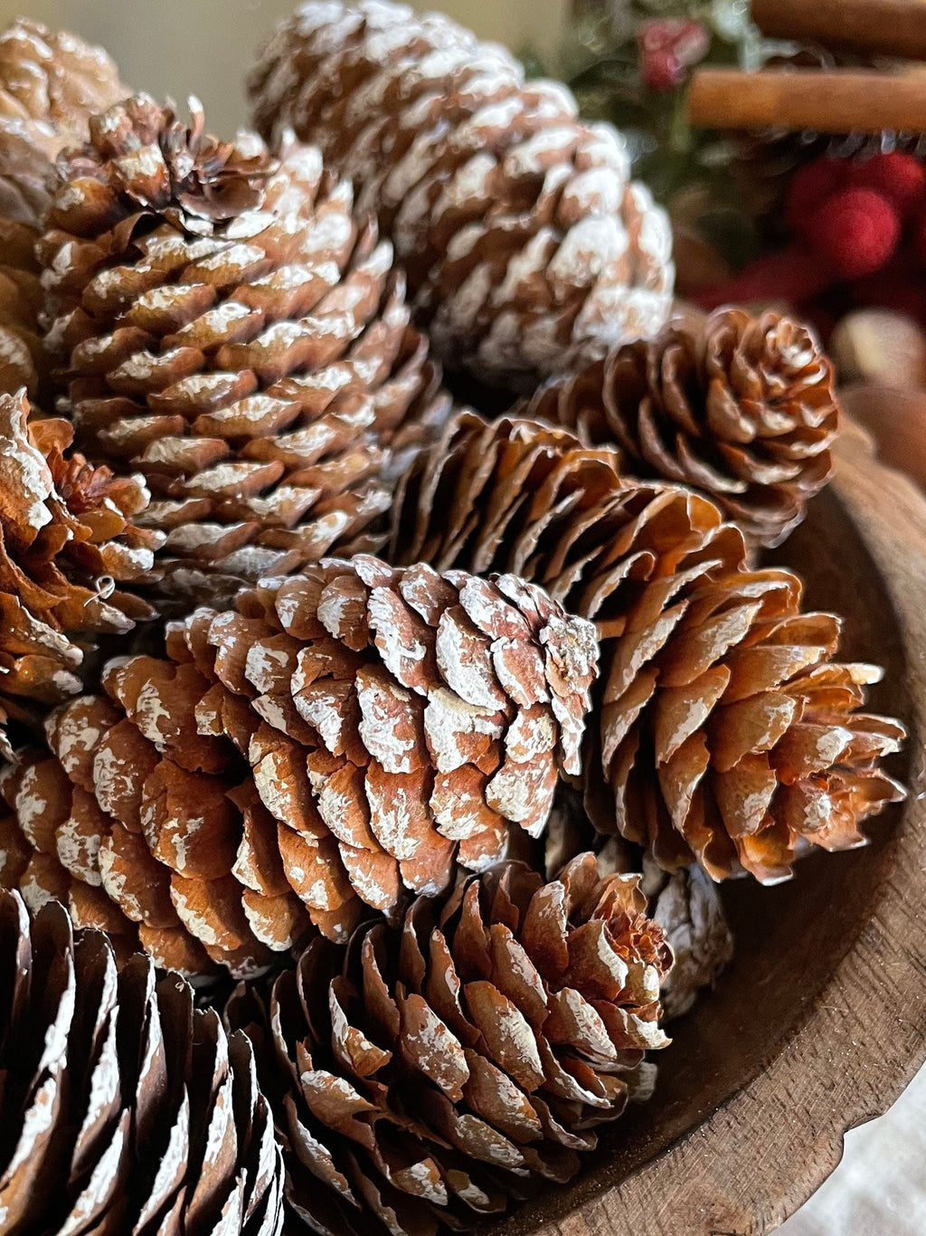 Decorative arrangement of pinecones in a wooden bowl with a blurred background