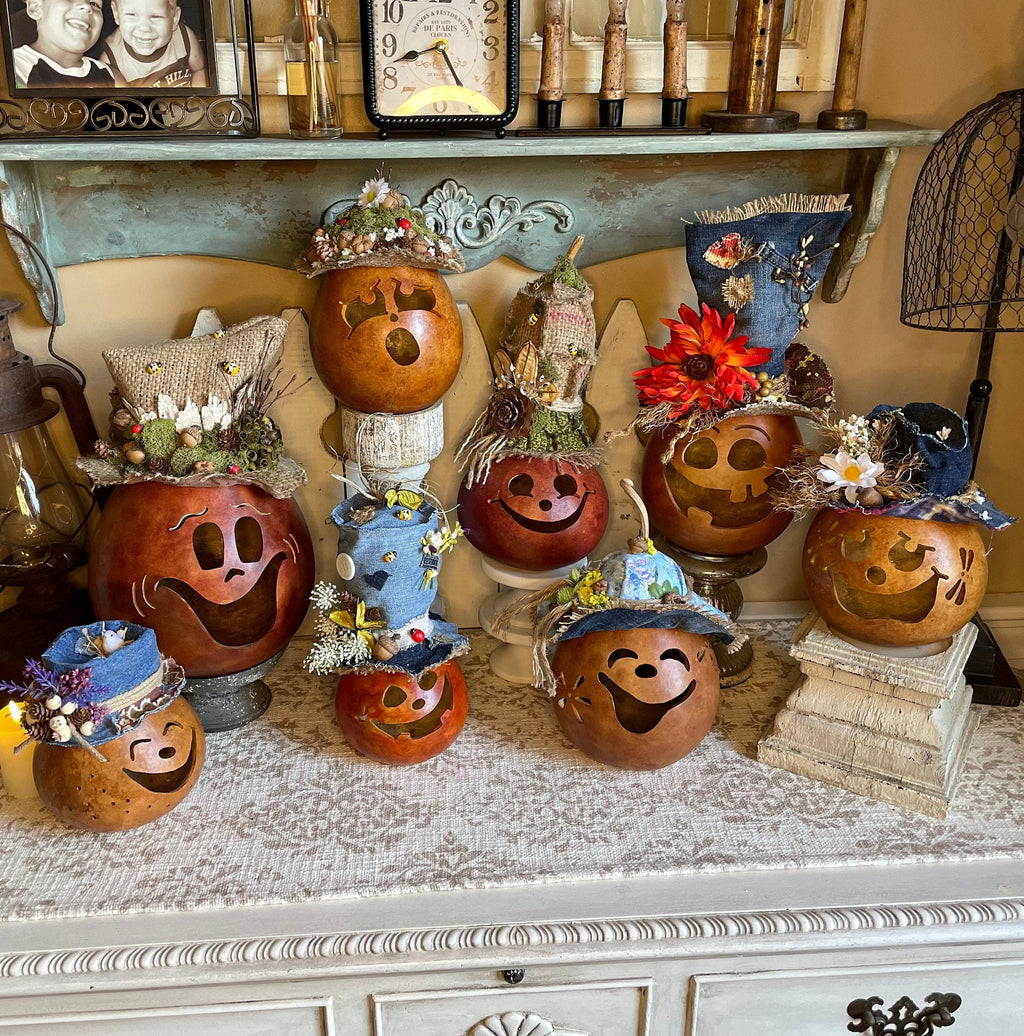 Decorative pumpkins with hats on a shelf with a clock and decorative items in the background.