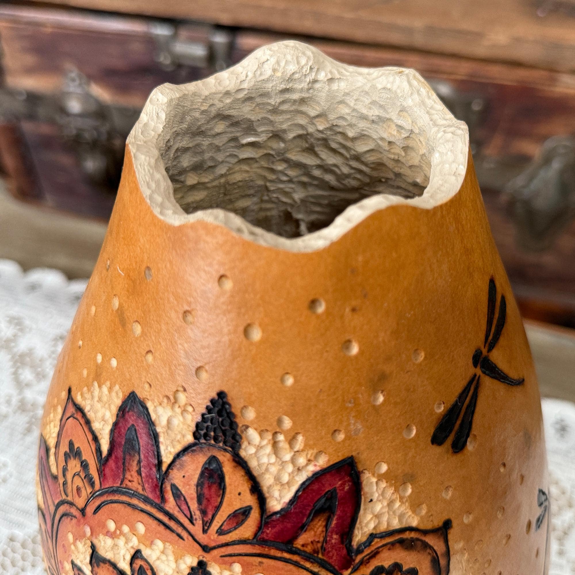 Decorative gourd with floral patterns and dragonflies on a textured surface