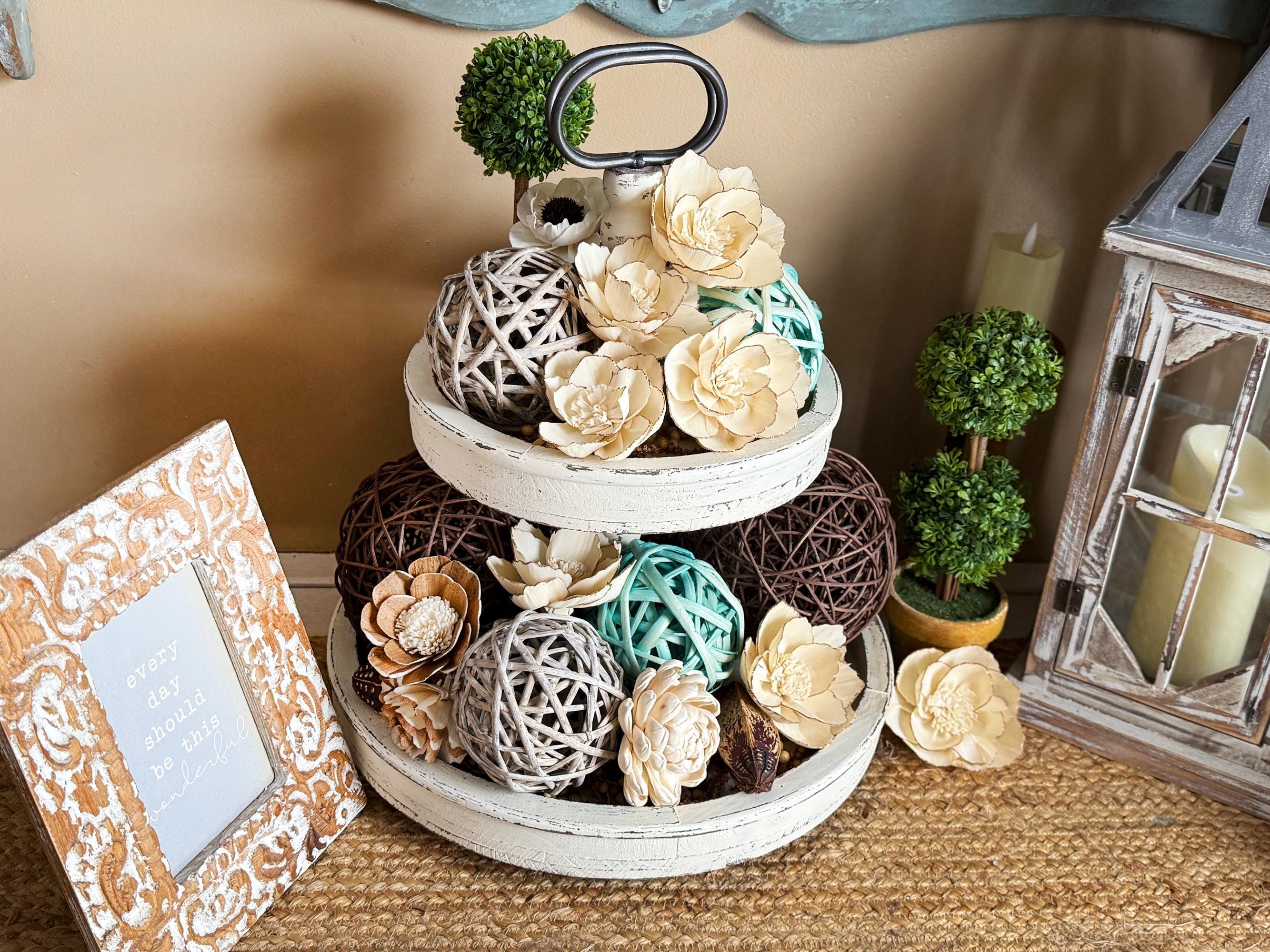 Decorative tiered tray with flowers and decorative items on a table.