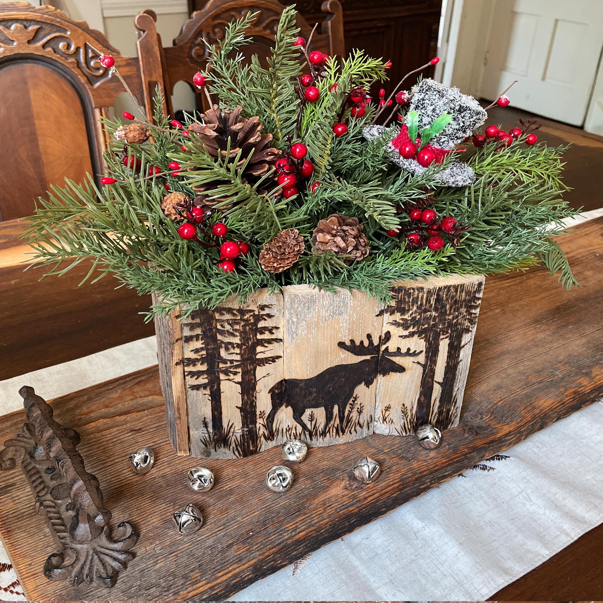 Decorative floral arrangement in a wooden box with a moose design on a rustic surface.