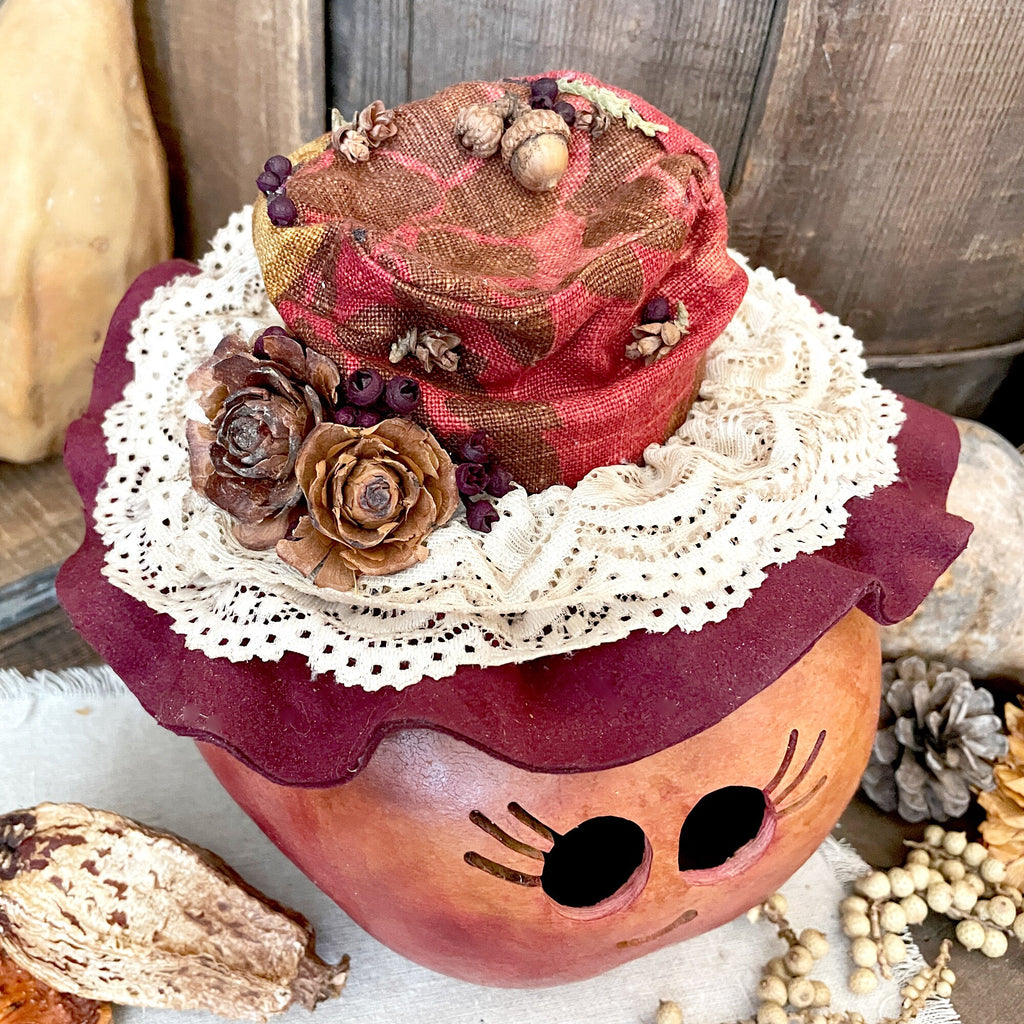 Decorative pumpkin with a hat, lace, and natural elements on a rustic background