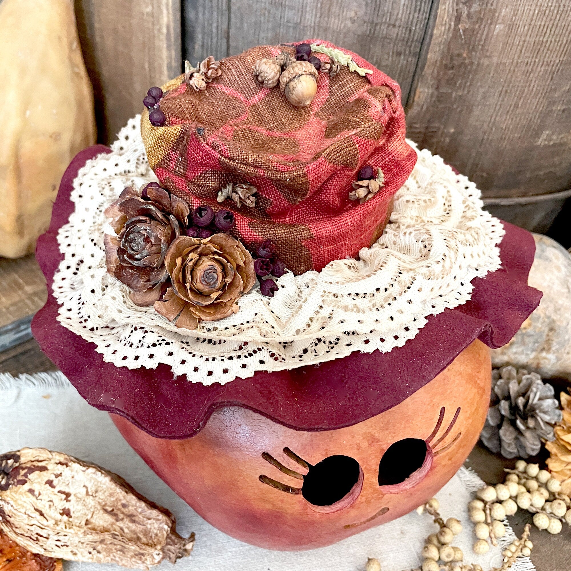 Decorative pumpkin with a hat, lace, and natural elements on a rustic background
