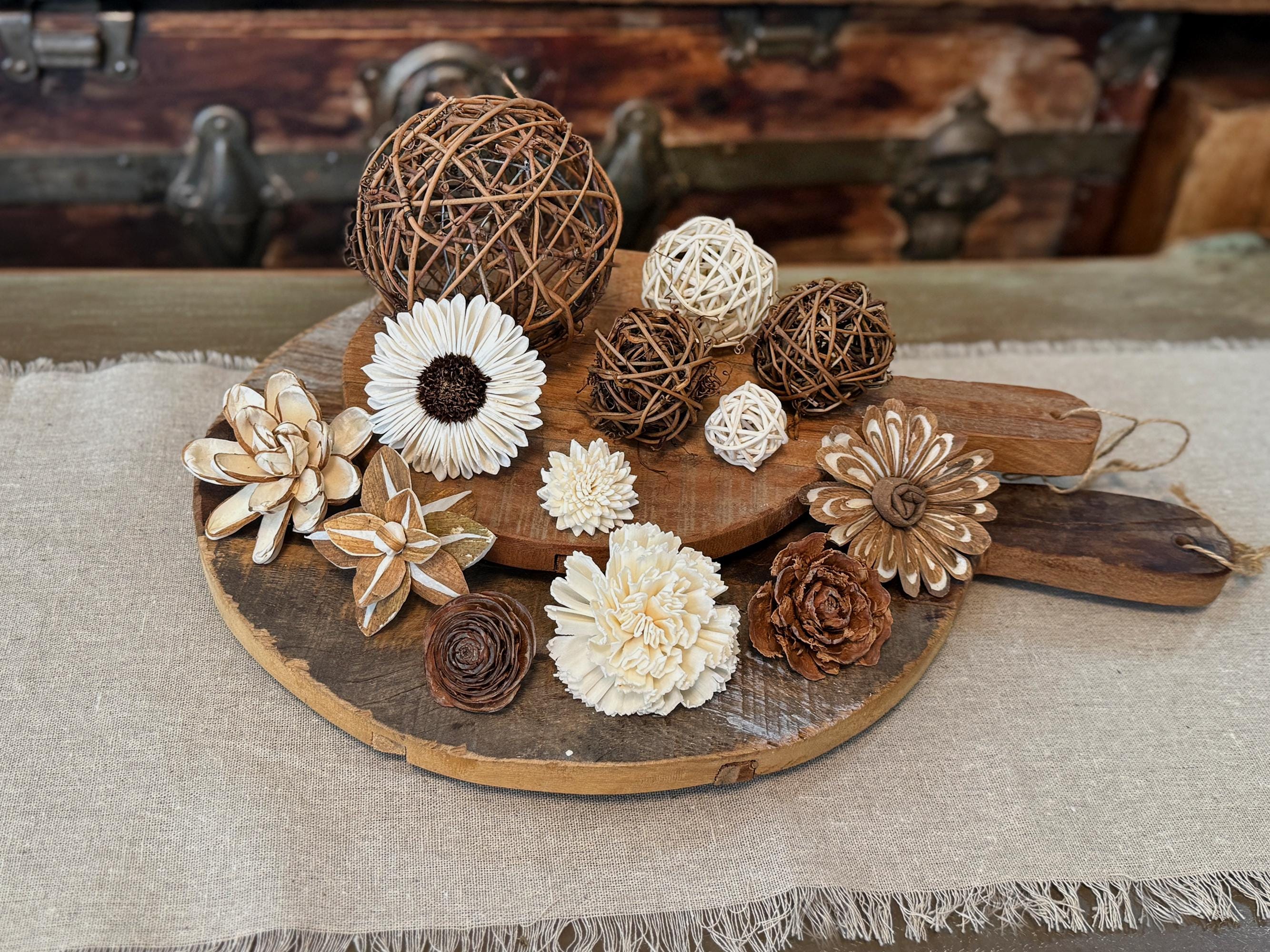 Decorative bowl filler kit including flowers and spherical objects on a wooden board with a rustic background.