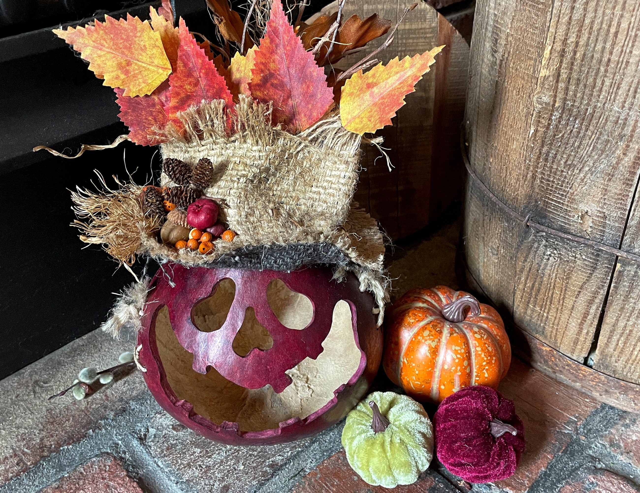 Decorative skull with autumn leaves and pumpkins on a stone surface