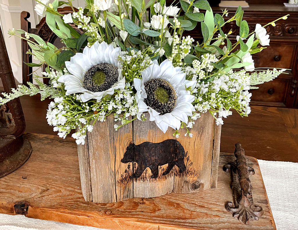 Floral arrangement in a wooden box with bear design on a wooden surface