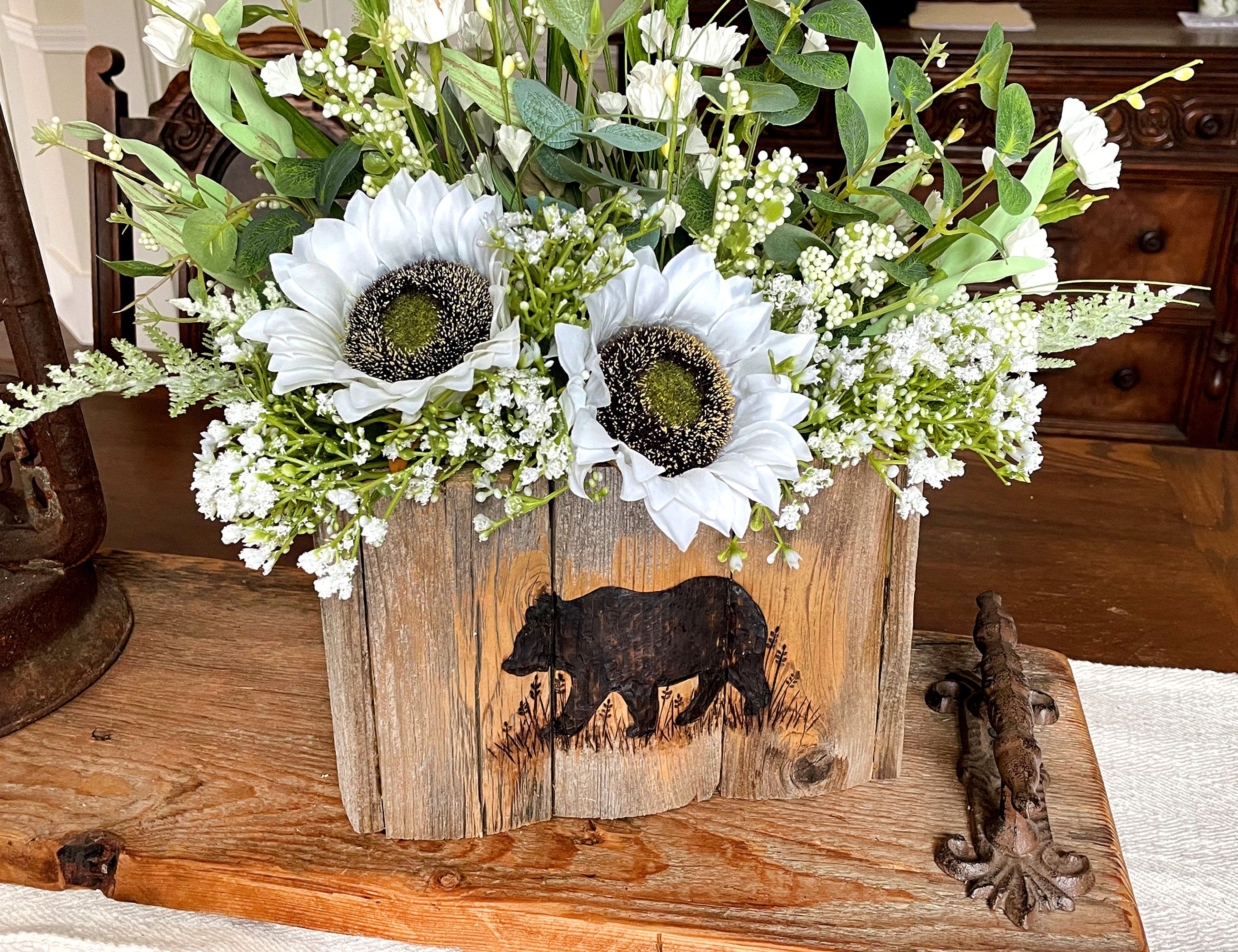 Floral arrangement in a wooden box with bear design on a wooden surface