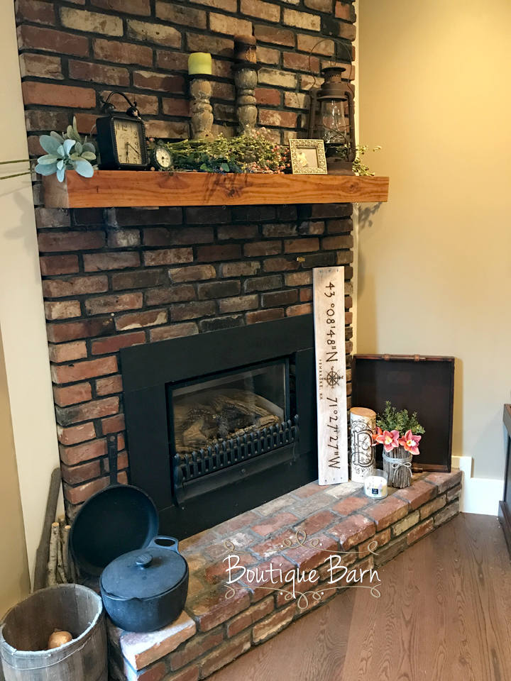Brick fireplace with wooden mantel and decorative items in a room.