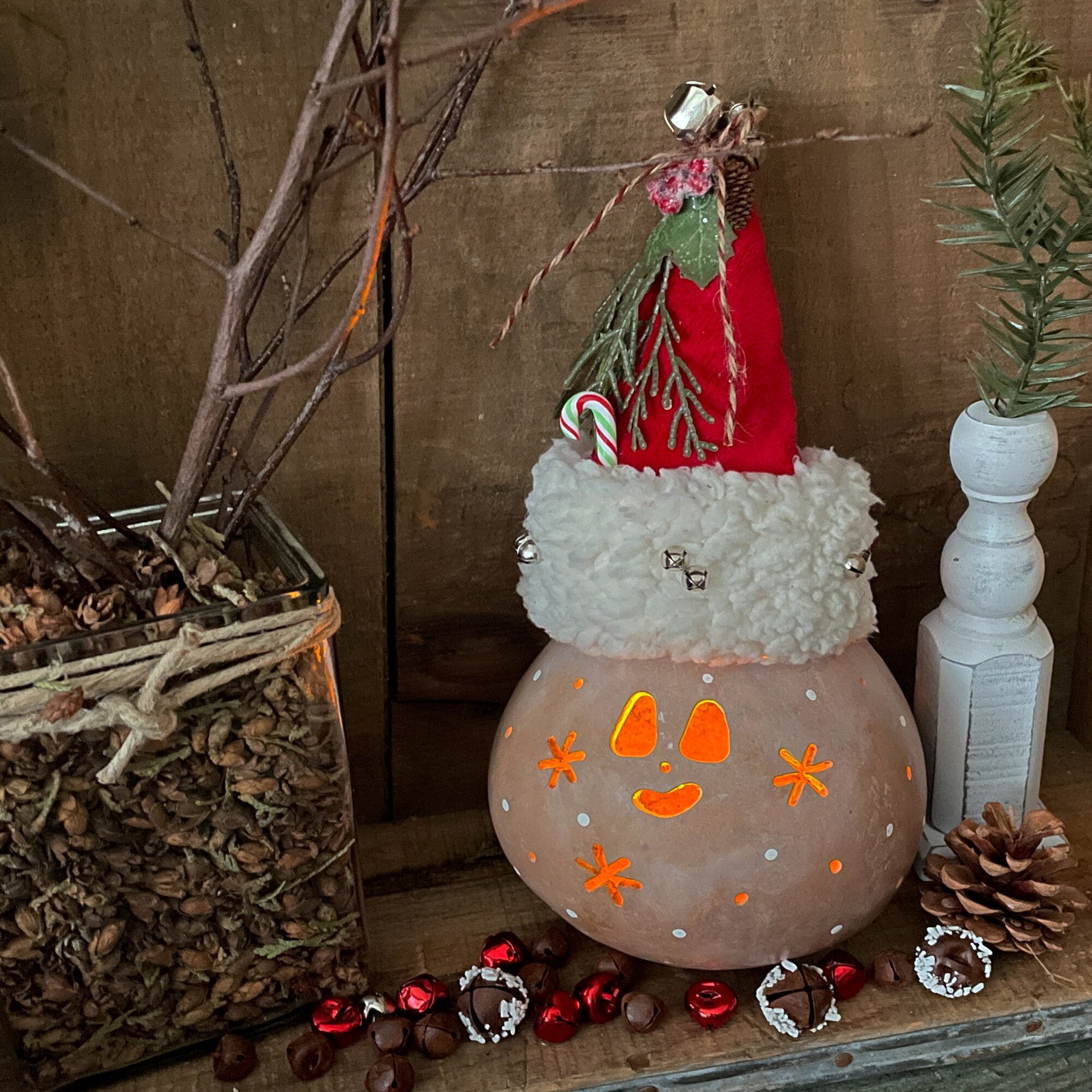 Decorative lantern with a face, surrounded by festive items on a wooden surface.