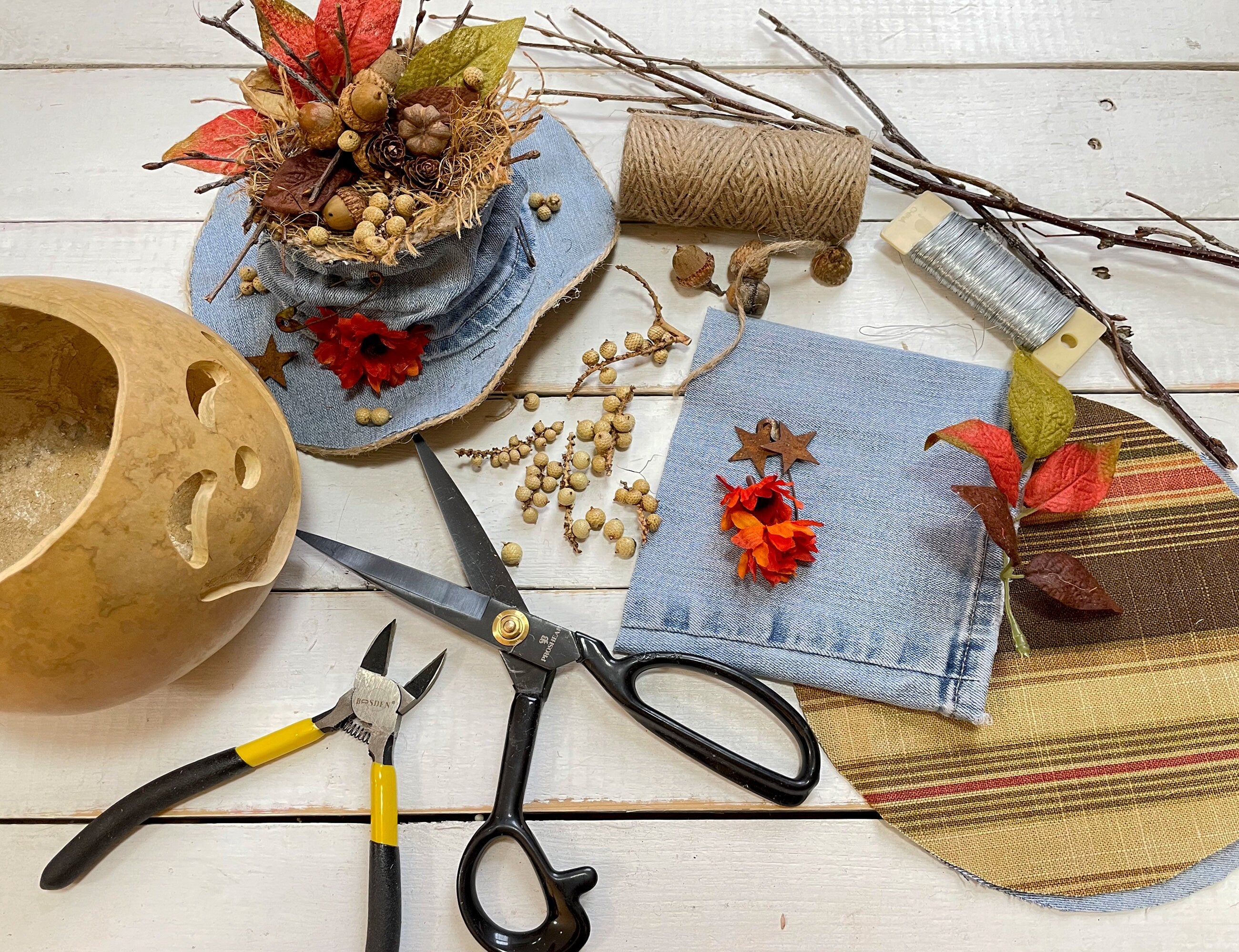 Crafting materials including scissors, pliers, fabric, and decorative elements on a wooden surface.