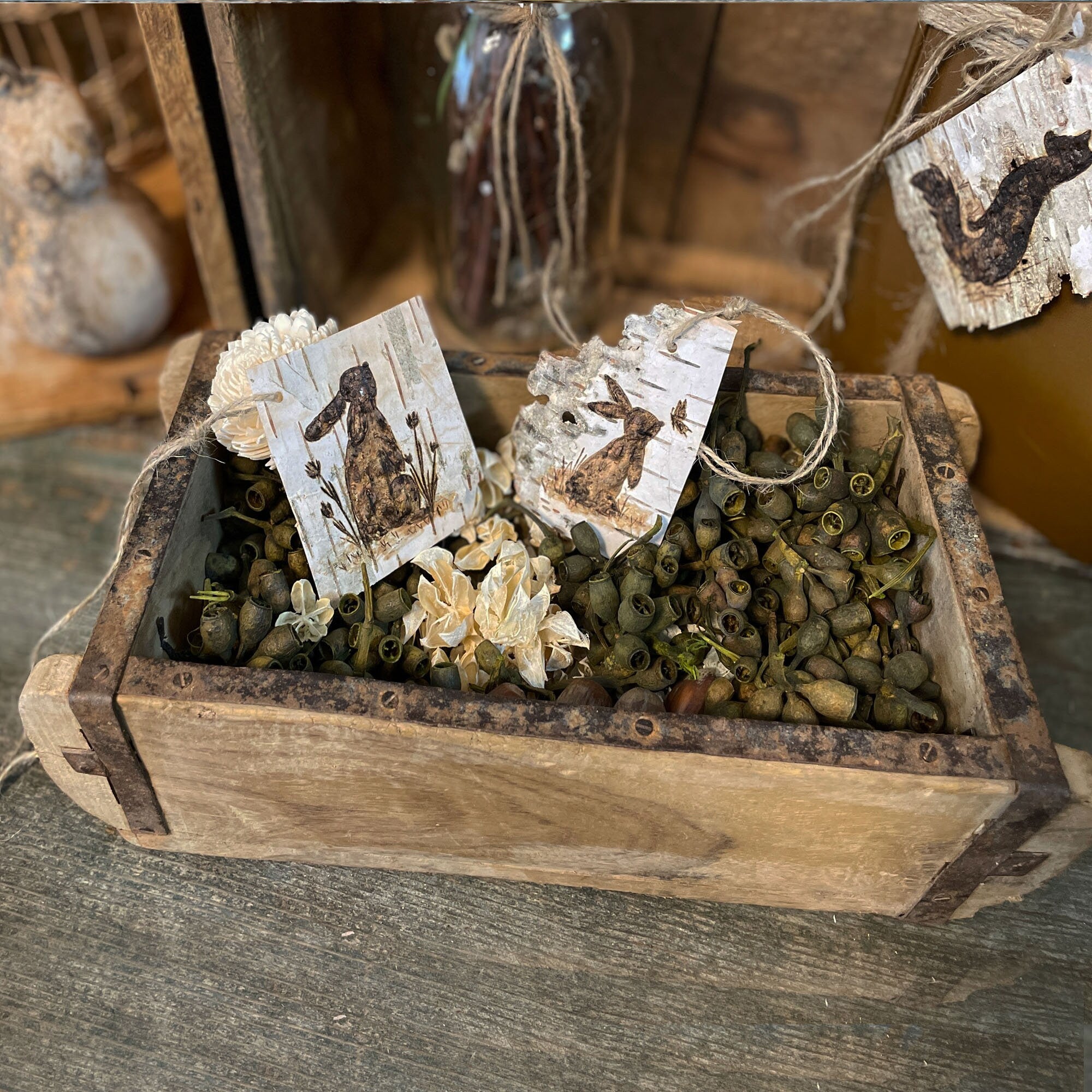 Wooden crate with dried plants and decorative birch bark tags on a rustic background