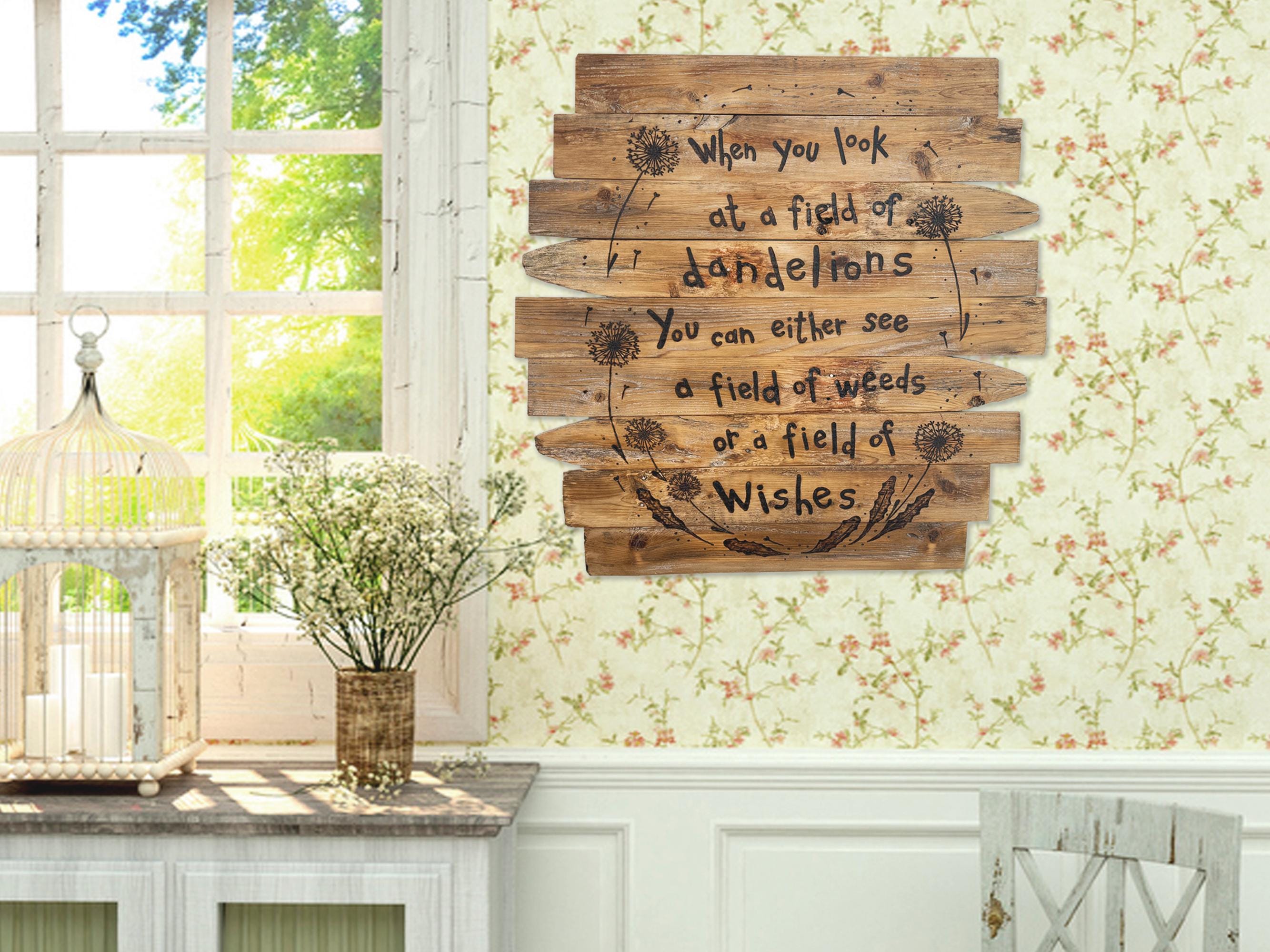 Wooden wall art with dandelion design and text in a home setting.