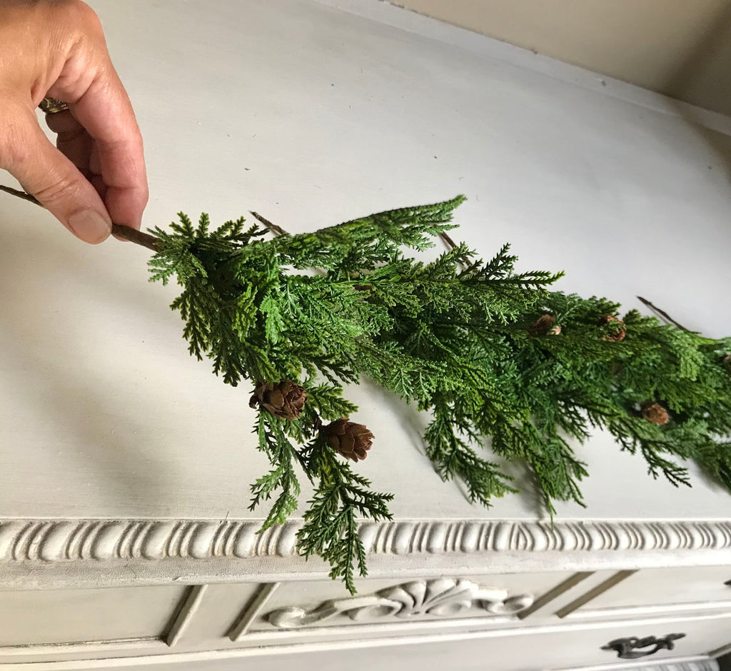 Hand arranging greenery on a decorative white surface